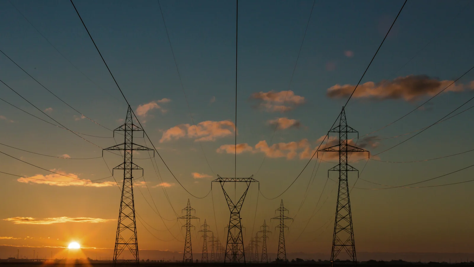 Expansive high-voltage transmission grid beneath a dramatic evening sky